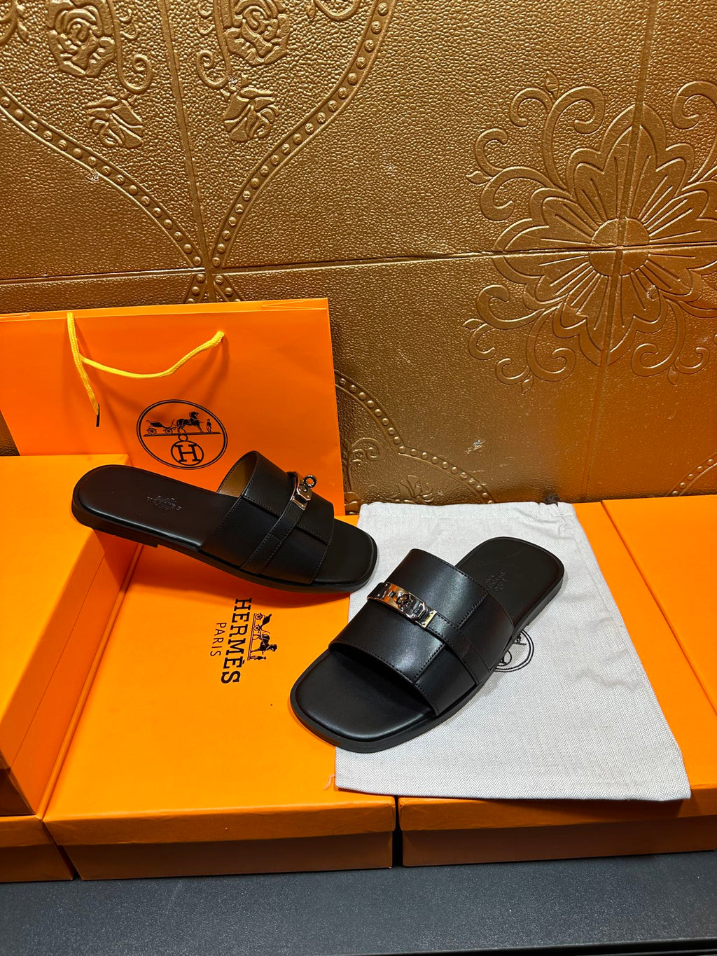 Hermes luxury black slide sandals on display with silver-tone buckle detail