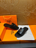 Hermes luxury black slide sandals on display with silver-tone buckle detail