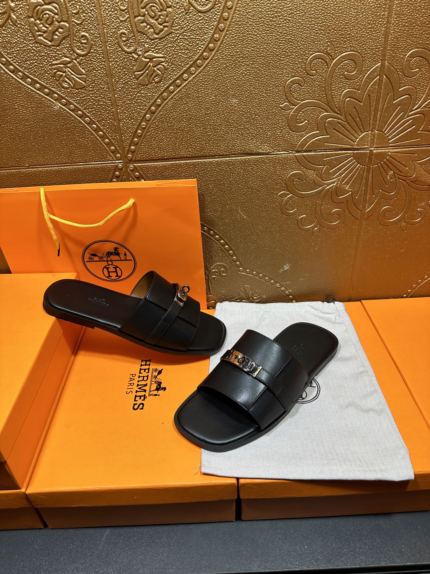 Hermes luxury black slide sandals on display with silver-tone buckle detail