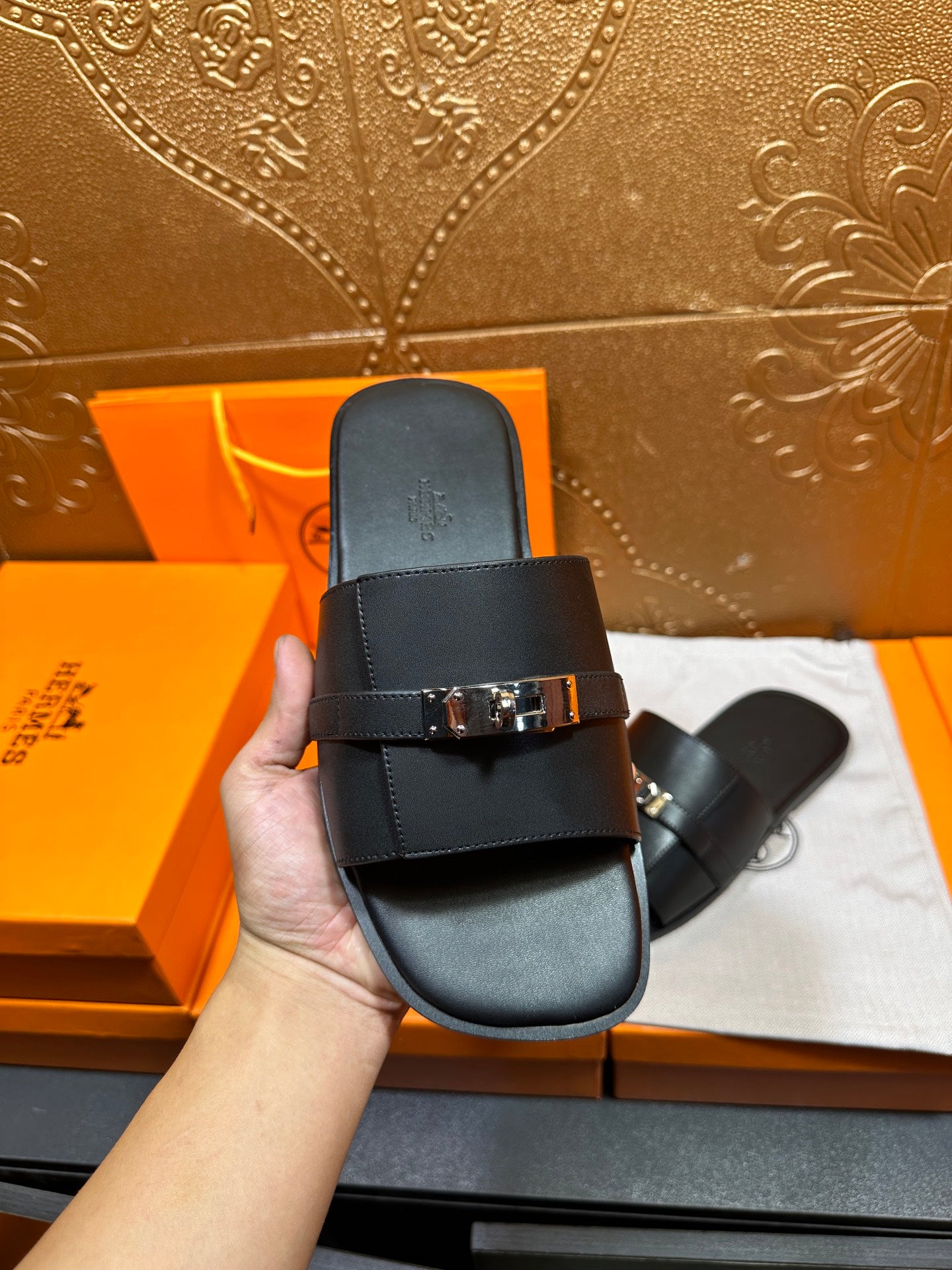 Hermes luxury black slide sandals, close view of wide strap and silver-tone buckle