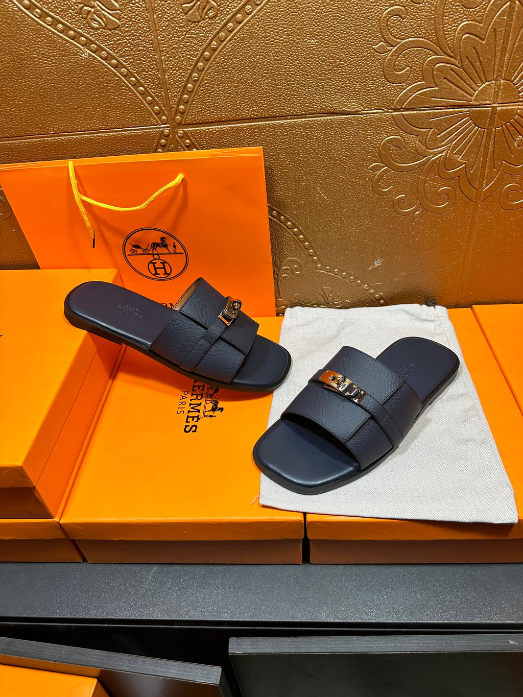 Navy leather slide sandals with gold-tone buckle, pair view