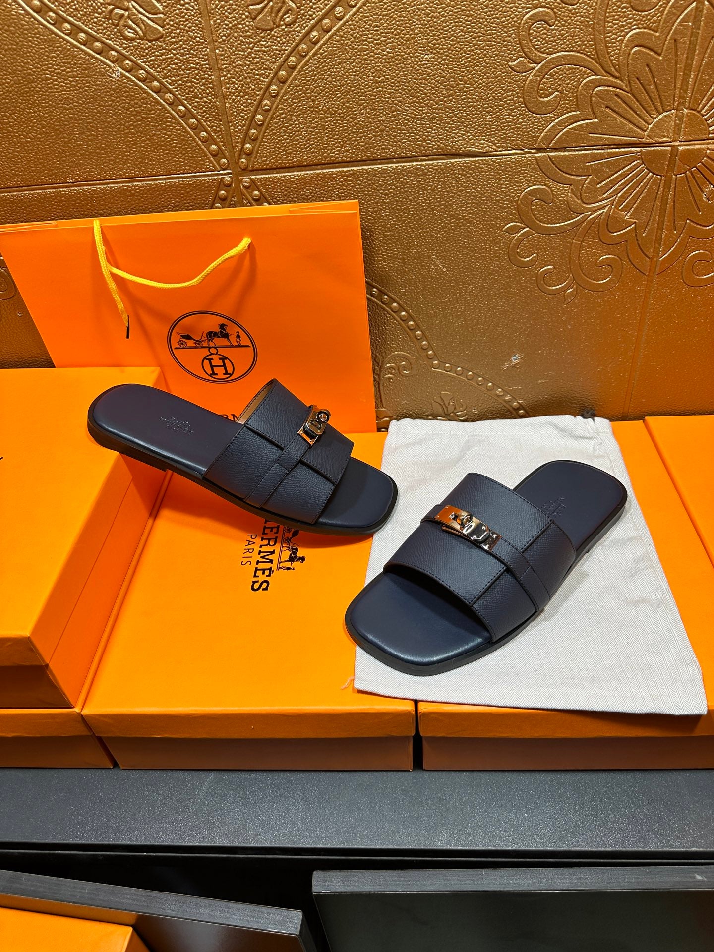 Navy leather slide sandals with gold-tone buckle, pair view