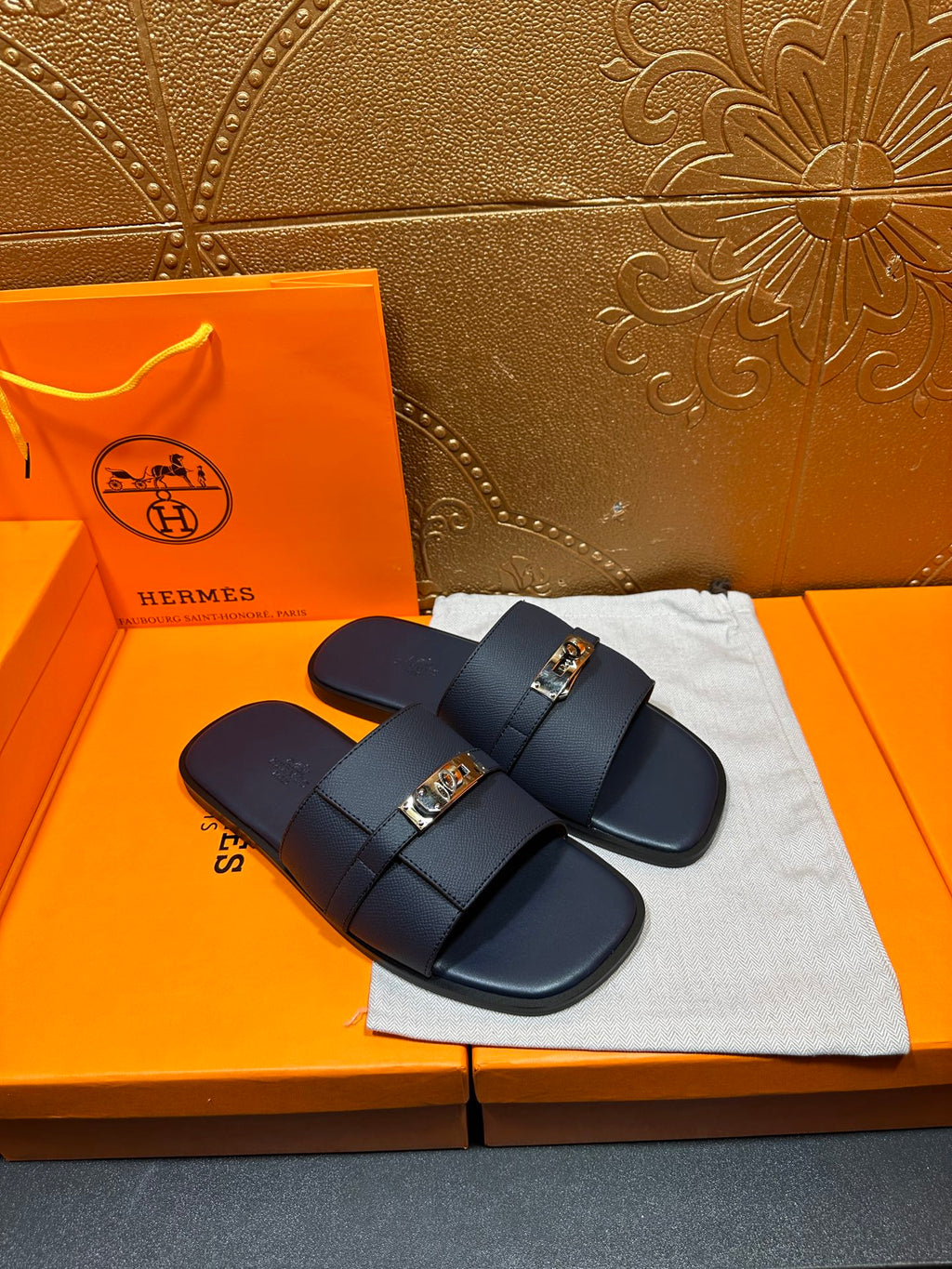 Navy leather sandals with crossed straps and gold-tone buckle detail