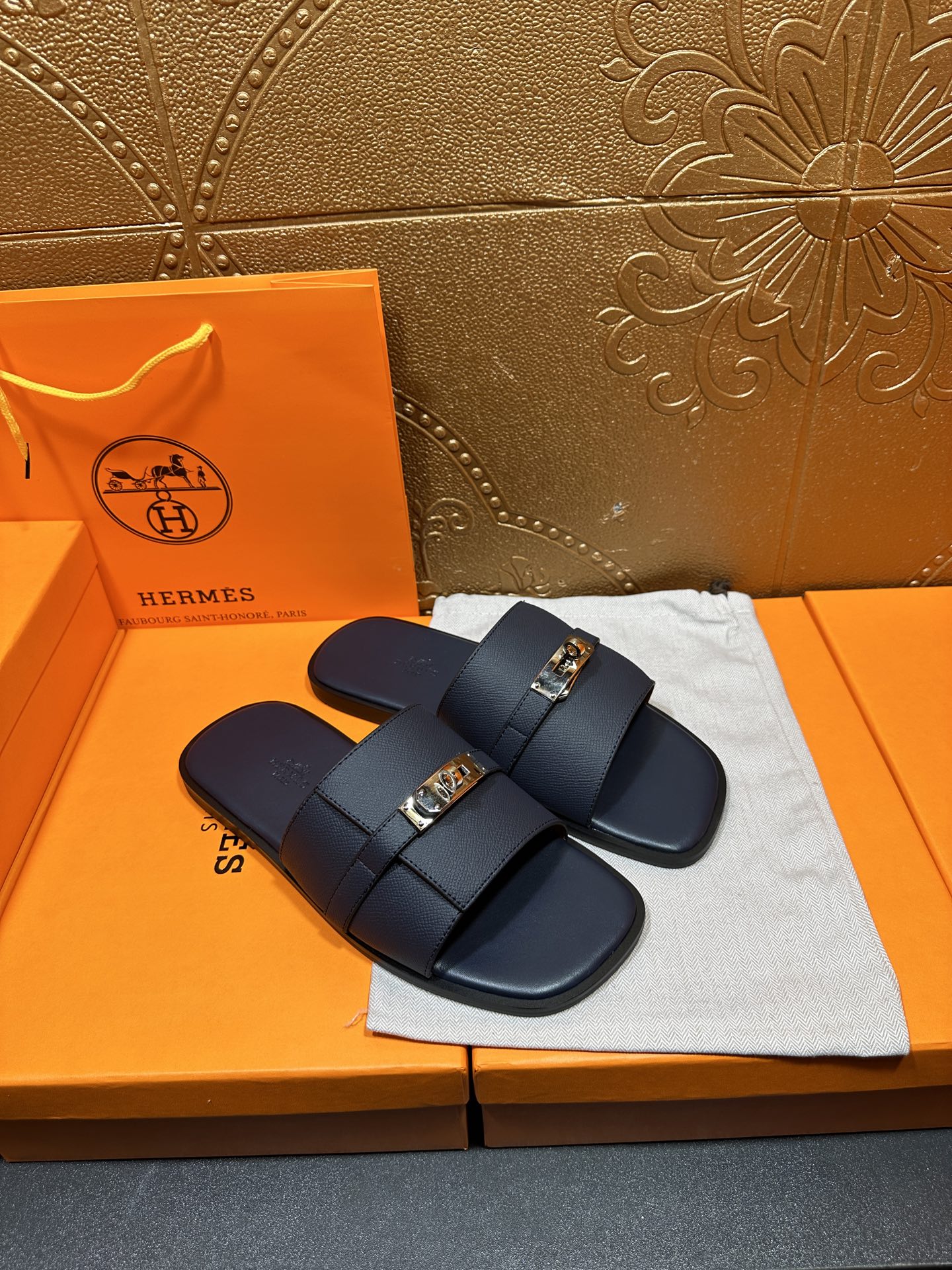 Navy leather sandals with crossed straps and gold-tone buckle detail
