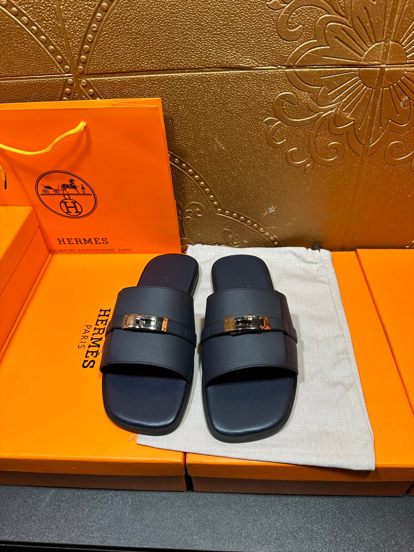 Navy leather slide sandals with adjustable strap and gold-tone buckle