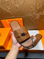 Brown leather slide sandal in hand with two straps and square buckle