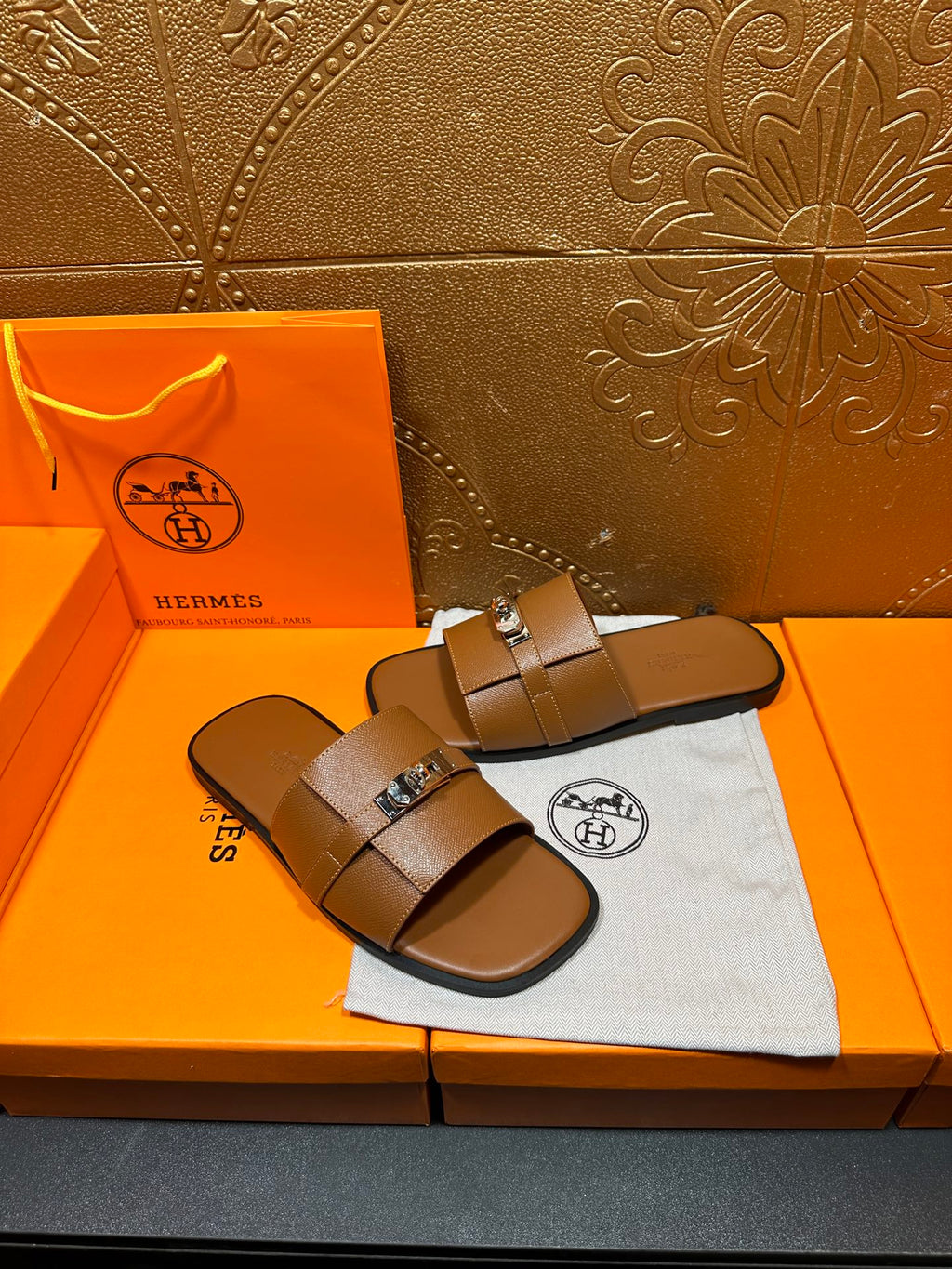 Brown leather slide sandals with two wide straps and square buckle, side angle