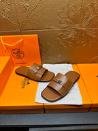 Brown leather slide sandals with two straps and square buckle, on dust bag
