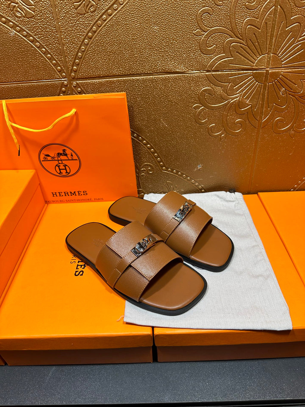 Brown leather slide sandals with double straps and square buckle, pair angled