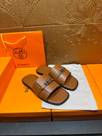 Brown leather slide sandals with double straps and square buckle, pair angled