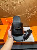 Hermes black leather slide sandal in hand, side profile and buckle hardware