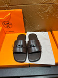 Brown leather slide sandals with adjustable buckle strap, open toe.