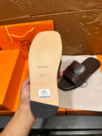 Tan sandal sole view with dark straps and buckle; bottom footbed visible.