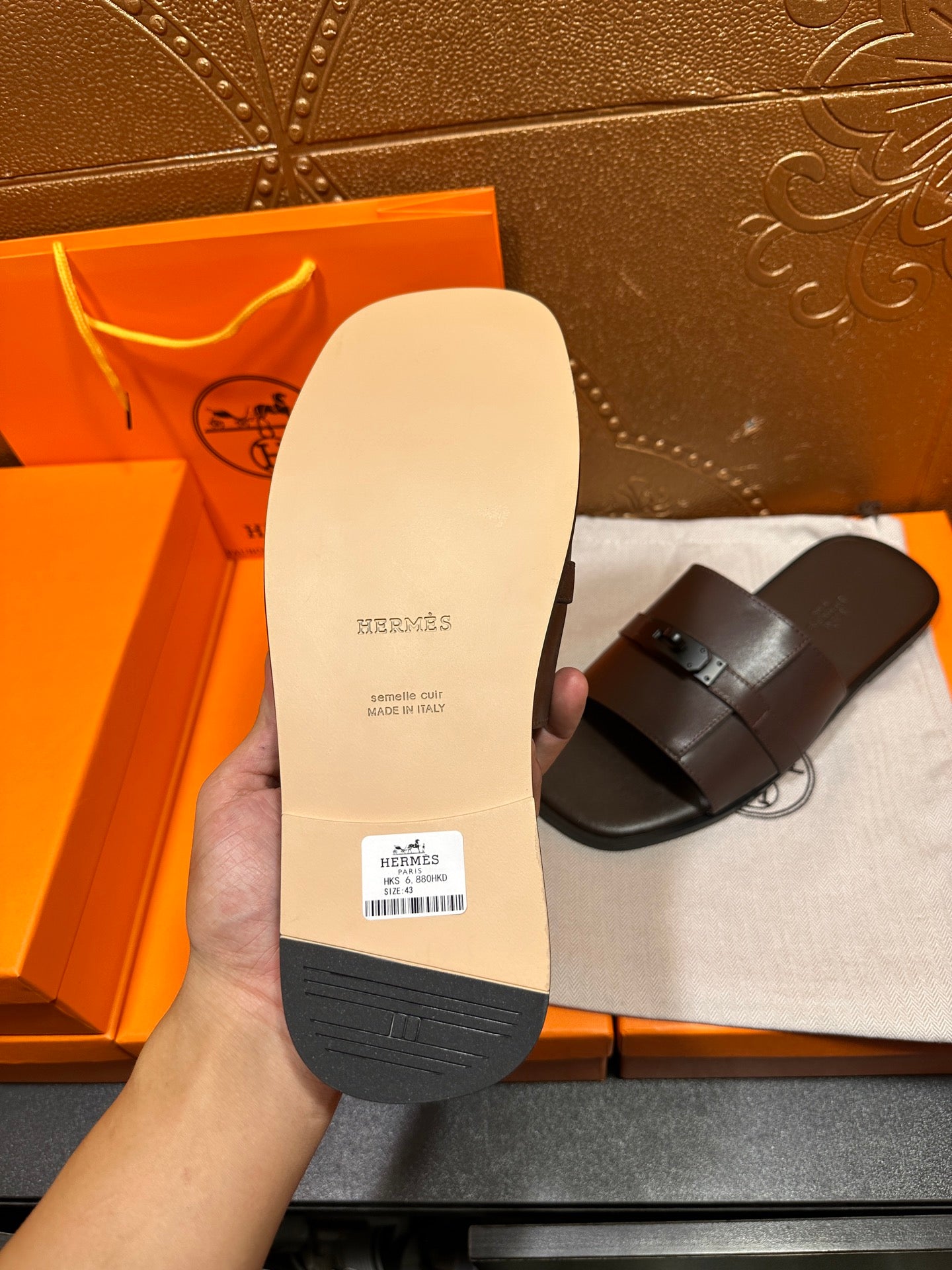 Tan sandal sole view with dark straps and buckle; bottom footbed visible.