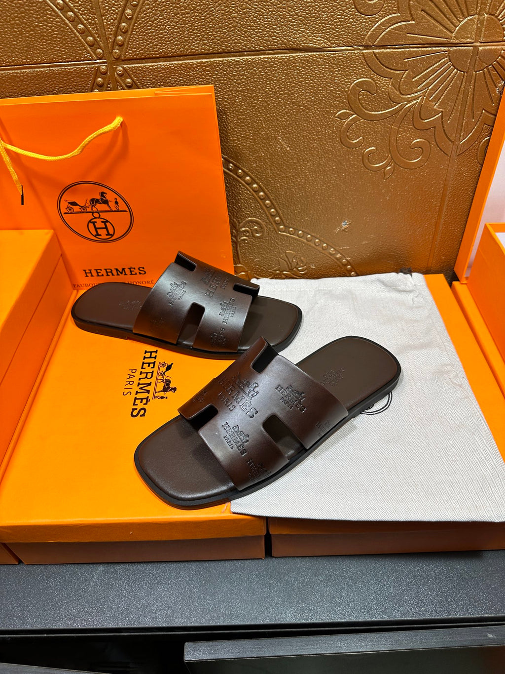 Brown leather slide sandals with HERMES logo embossed on the straps