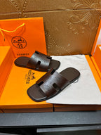 Brown leather slide sandals with HERMES logo embossed on the straps