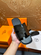Hermes black slide sandal held in hand, embossed straps, open toe