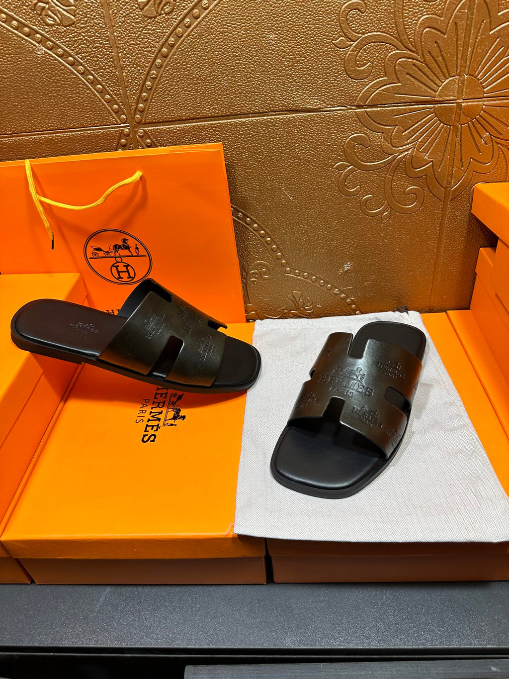 Hermes black slide sandals with embossed straps and open toe, paired set
