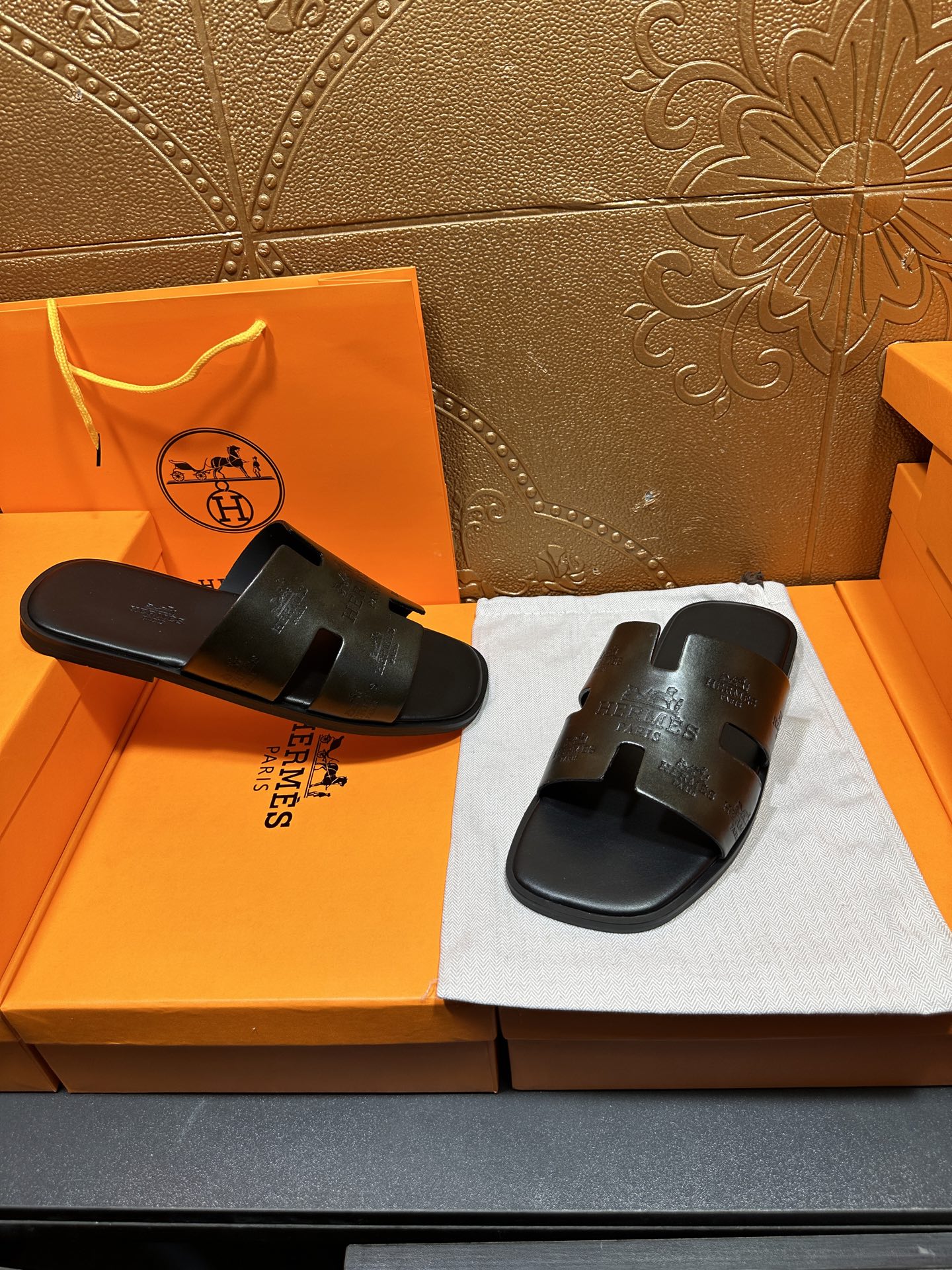 Hermes black slide sandals with embossed straps and open toe, paired set