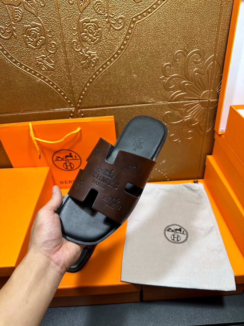 Hermes slide sandals on display; black molded footbed and dark embossed strap