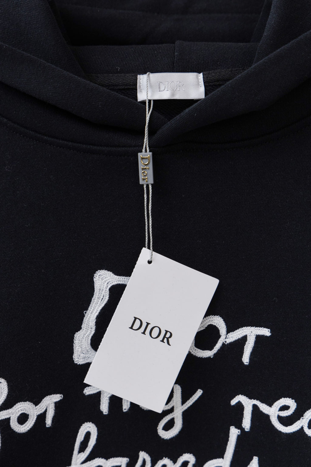 Dior black hoodie with 'Dior' hanging tag over the chest graphic