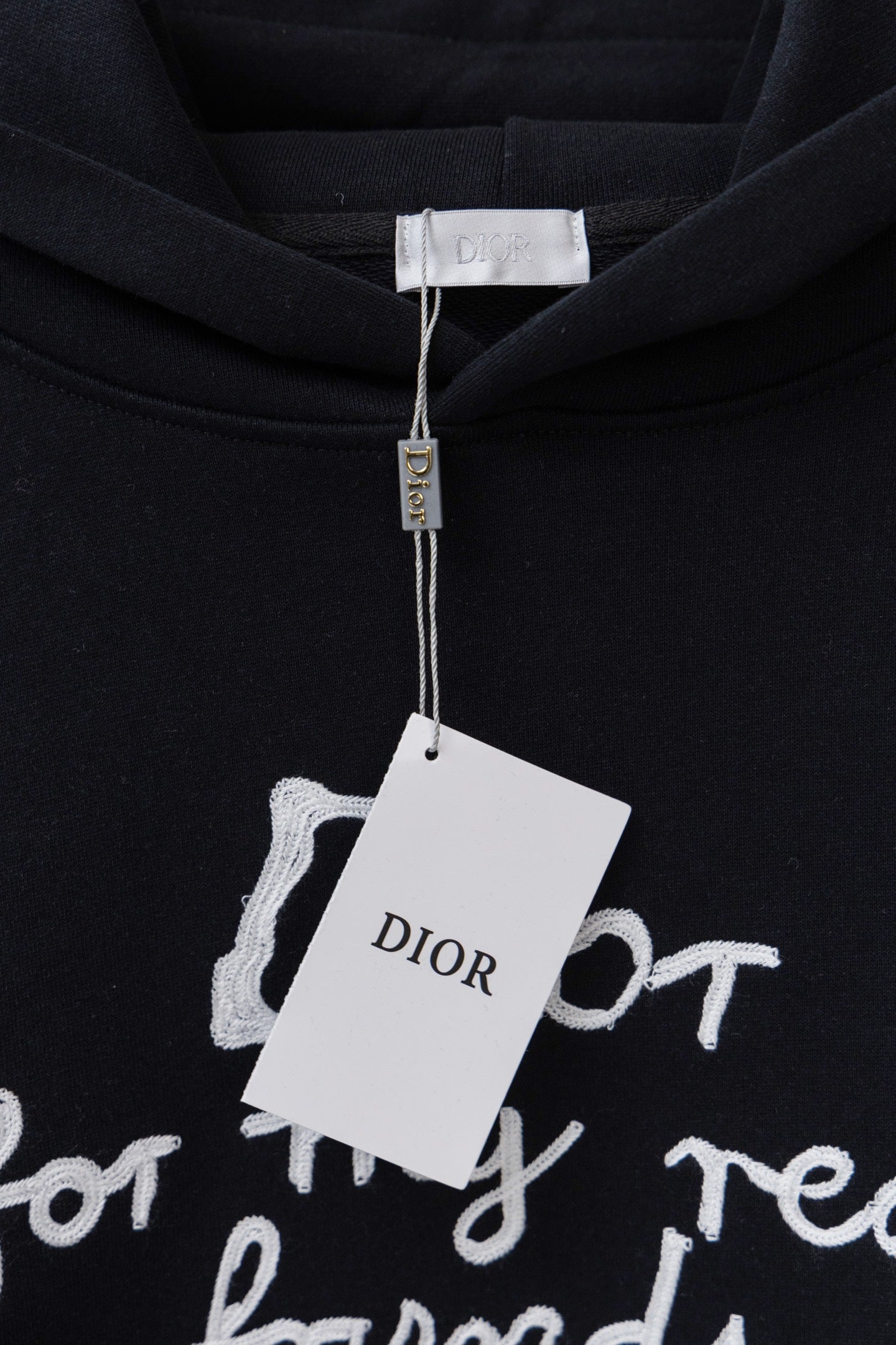 Dior black hoodie with 'Dior' hanging tag over the chest graphic