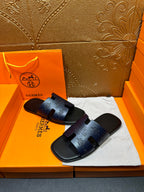 Hermes slide sandals, dark blue, side-by-side pair with embossed lettering on straps