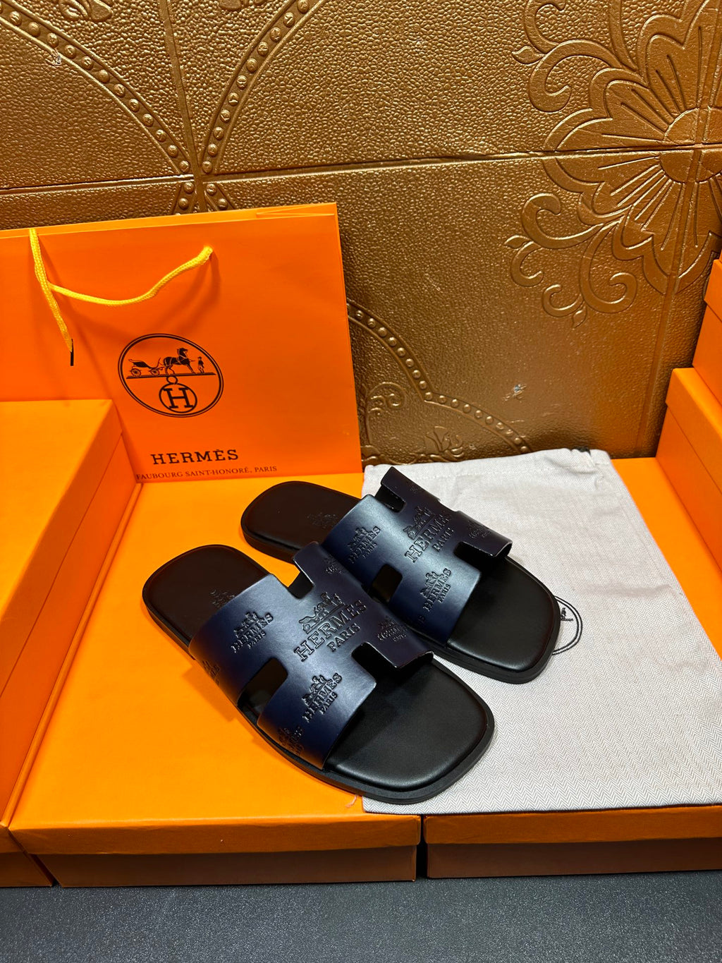 Hermes slide sandals in dark blue, angled view of wide strap and footbed