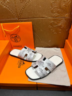Hermes white slide sandals with black logo print straps and molded footbed