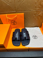 Hermes slide sandals, dark blue, embossed logo straps; pair on retail box.
