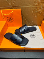 Hermes dark blue slide sandals, embossed strap details, shown on box with cloth.