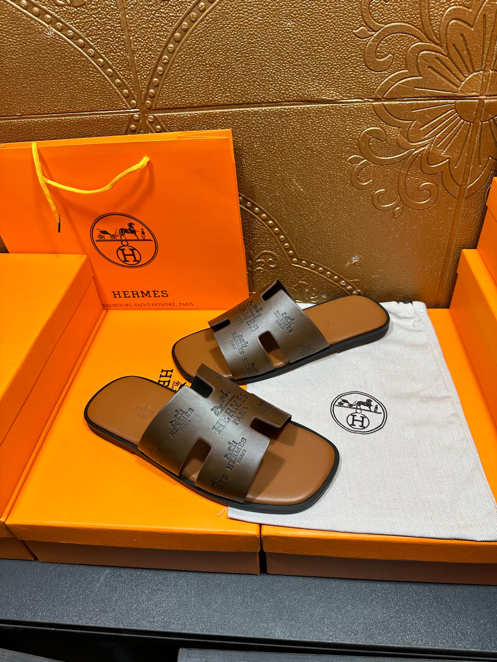 Dark gray leather slide sandals with stamped logo detail on straps