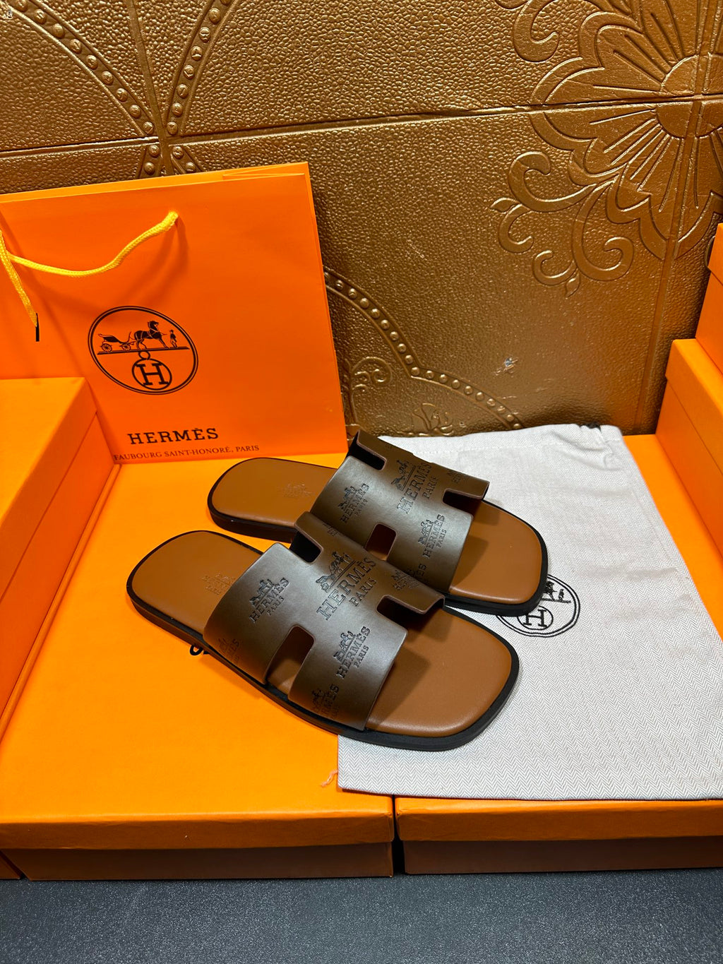Pair of dark gray logo slide sandals on a cloth with open toe