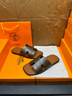 Dark gray slide sandals with embossed logos on wide straps and flat sole