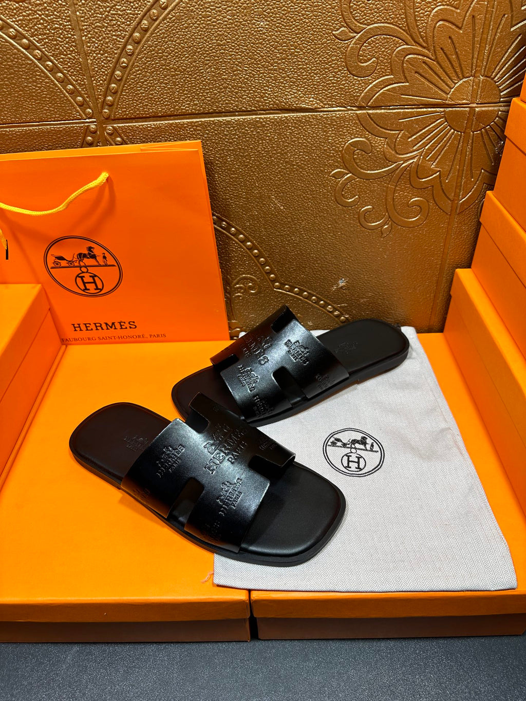 Hermes black leather slide sandals with wide embossed strap, side angle