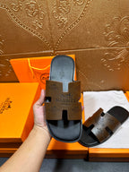 Hermes slide sandals held upright, dark brown footbed with cutout sole detail