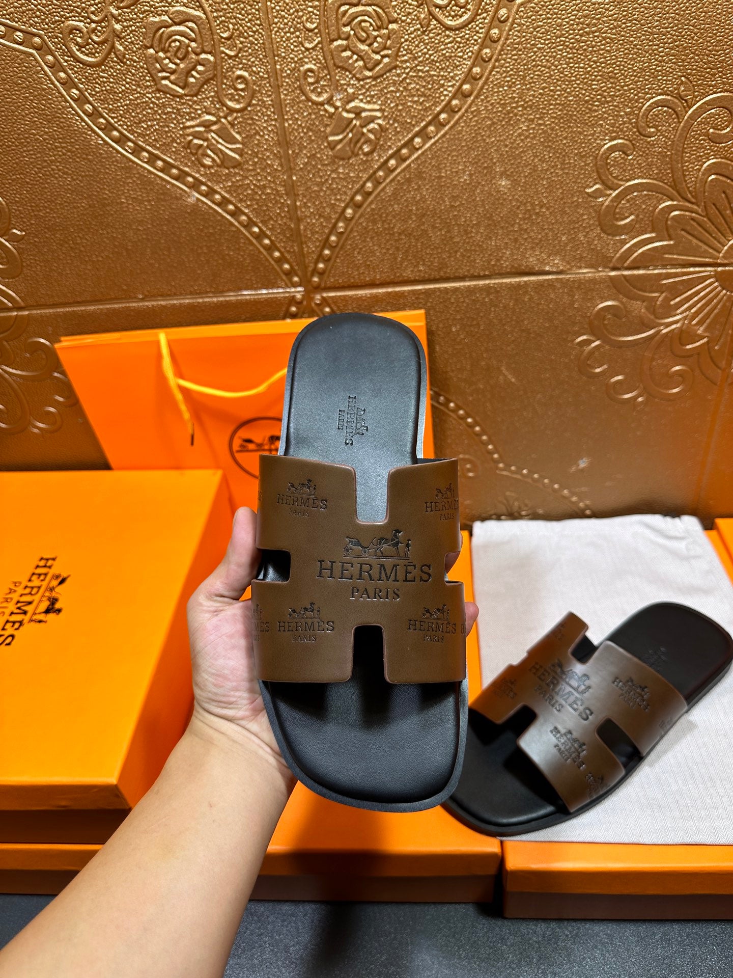 Hermes slide sandals held upright, dark brown footbed with cutout sole detail