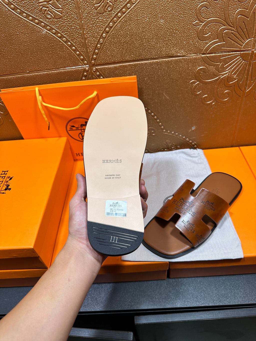 Hermes leather slide sandal sole in hand, light tan underside with logo markings