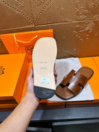 Hermes leather slide sandal sole in hand, light tan underside with logo markings