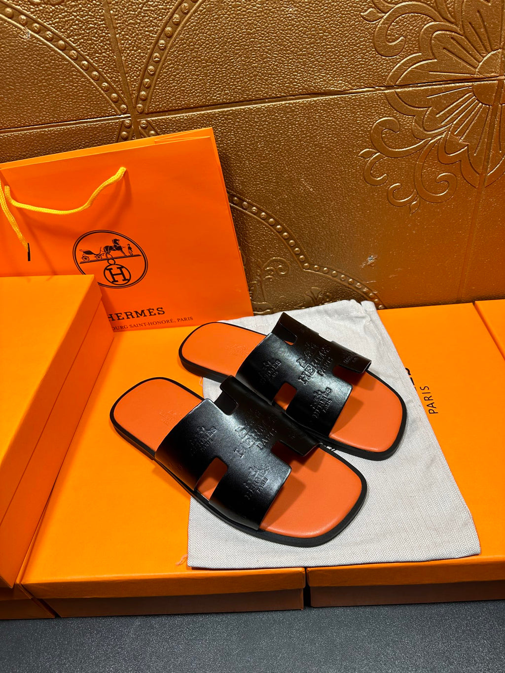 Hermes slide sandals: black embossed strap, orange footbed, pair