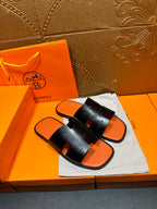 Hermes slide sandals: black embossed strap, orange footbed, pair