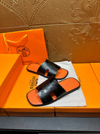Hermes slide sandals, black strap with orange footbed, angled view