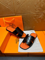 Hermes slide sandals, black embossed straps and orange footbed, pair