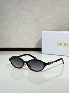 Black oval sunglasses with gold hinge logo and dark gray lenses