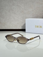 Black oval sunglasses with gold hinge logo and light brown lenses