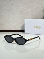 Black oval sunglasses with gold hinge logo and dark lenses
