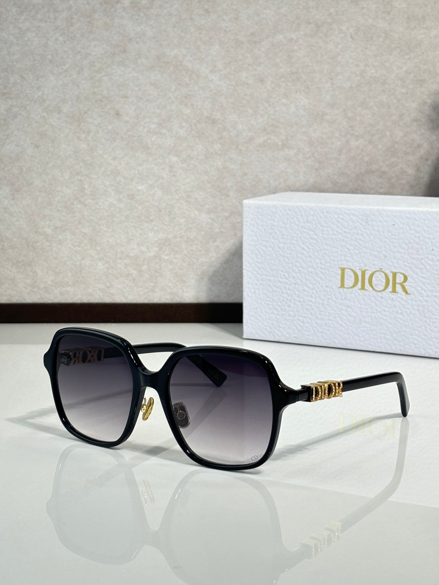 Dior sunglasses with black frame and dark lenses, gold hinge detail