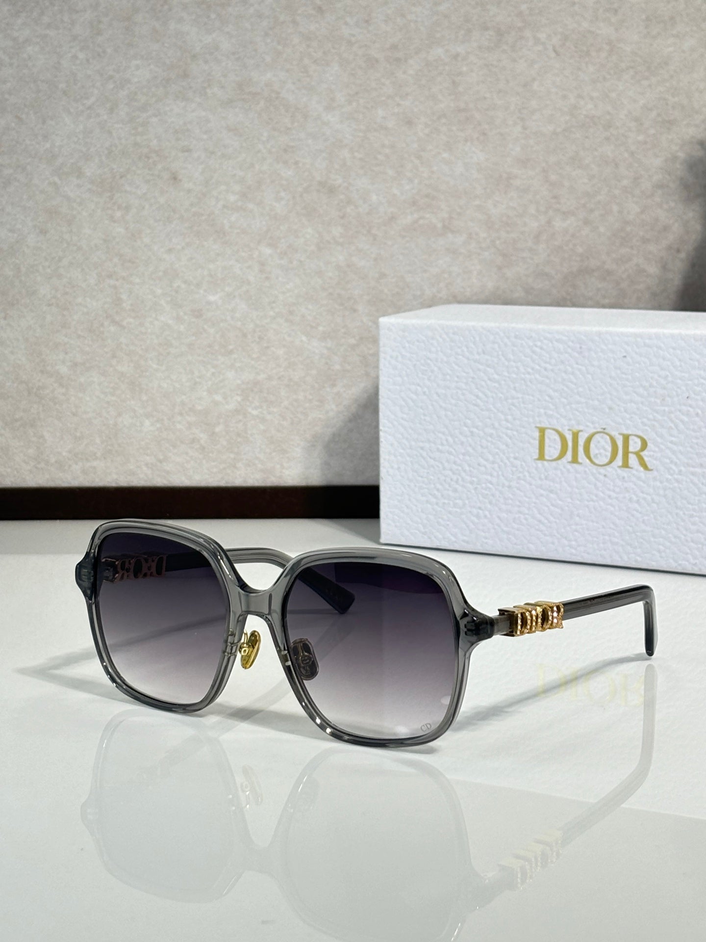 Dior sunglasses with translucent gray frame and dark tinted lenses, gold accents