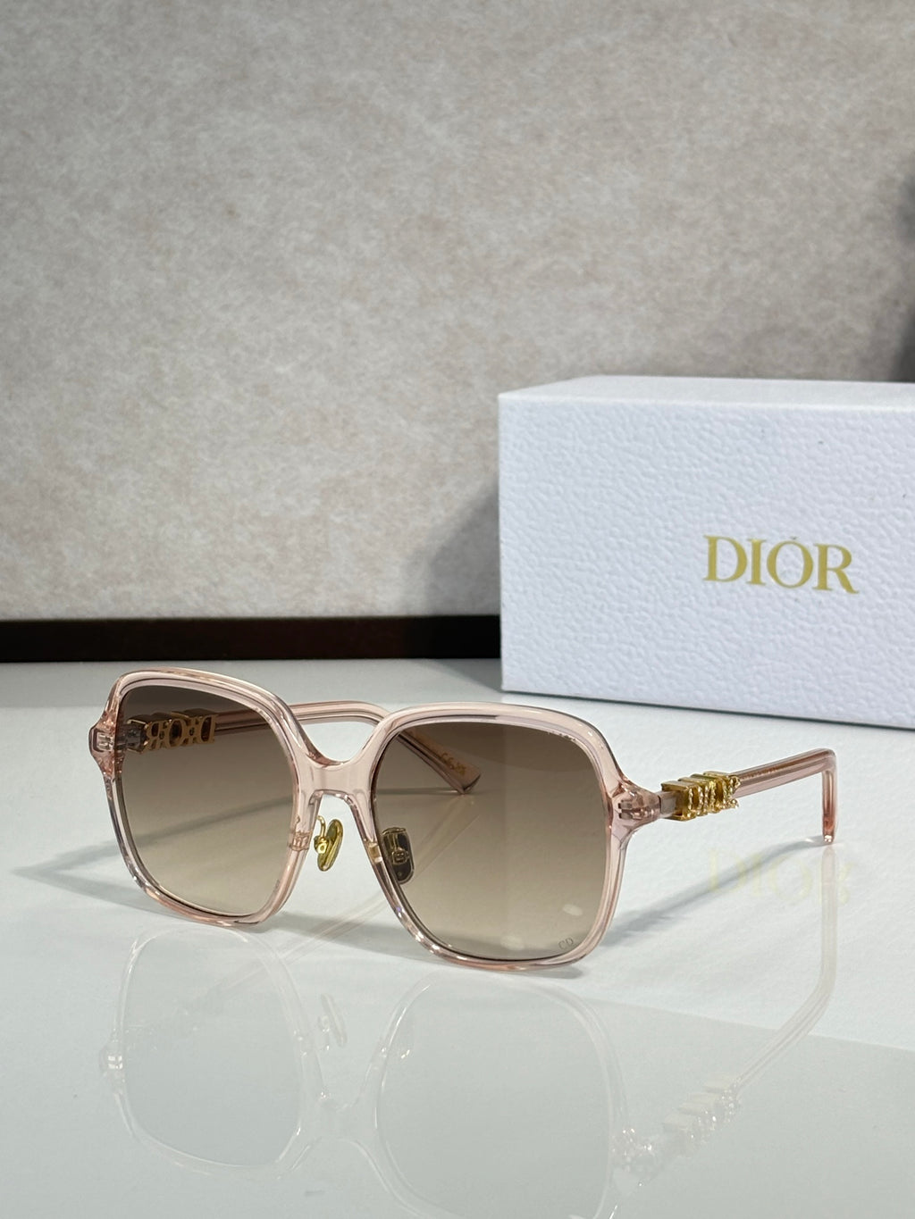 Dior sunglasses with rose-gold frame and light lenses, gold accents