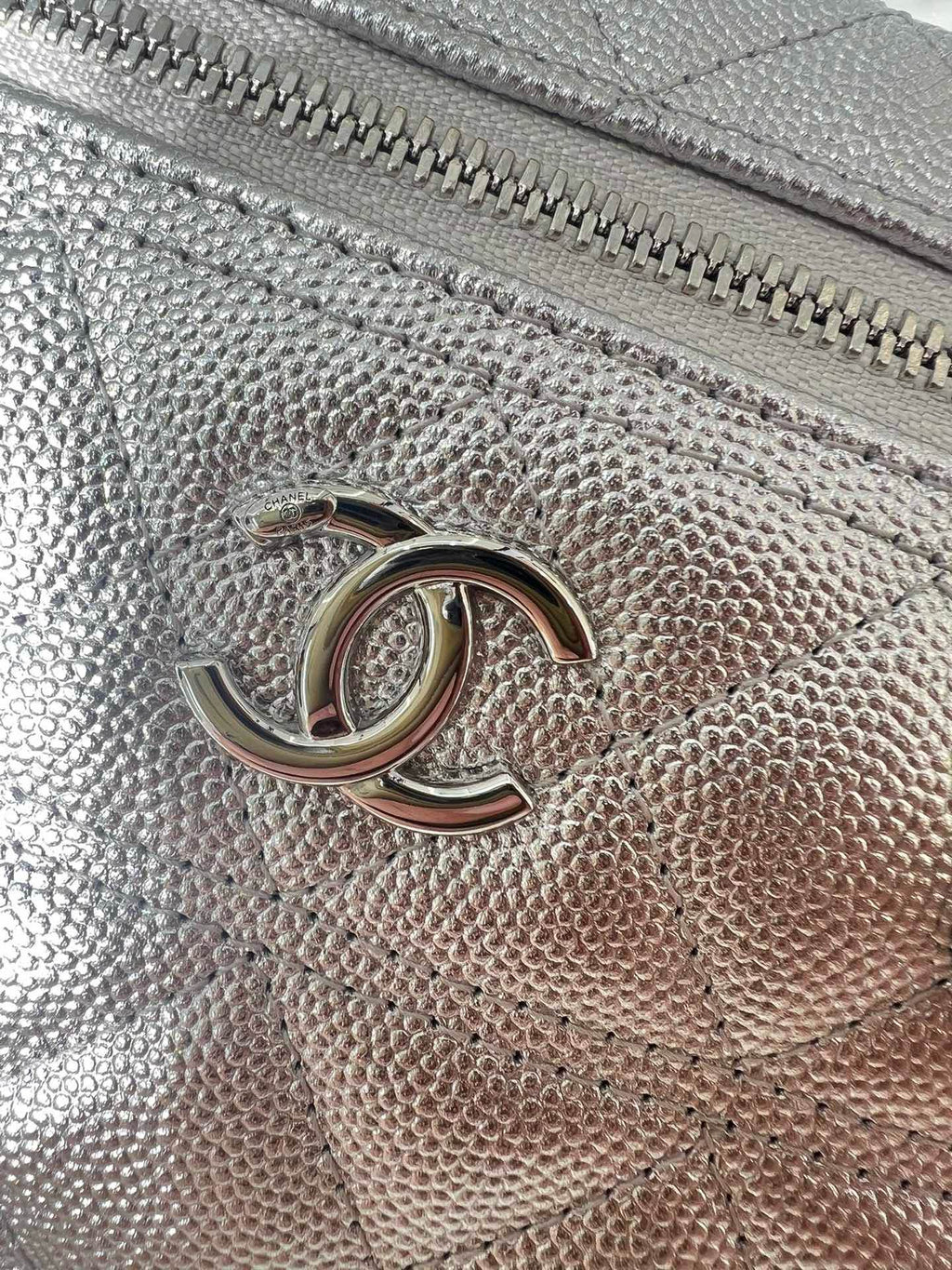 Chanel logo hardware on silver-tone quilted bag front with zipper track close-up